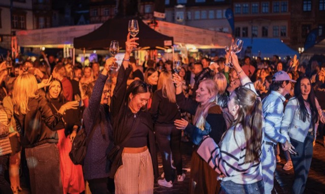 Gaeste stossen bei einem Stadtfest mit Getraenken an